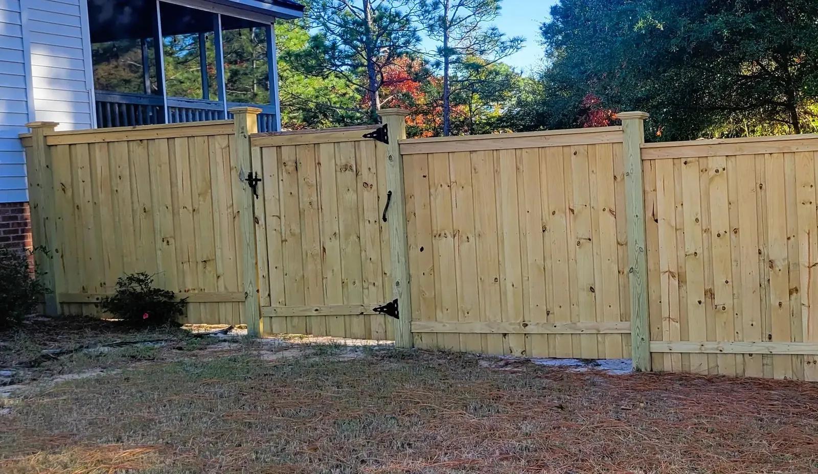 Wood step-down fence gate following a sloped yard in Wilmington, NC with consistent picket height and clean transitions.